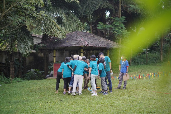 Peserta outbound training bekerja sama dalam kelompok di lapangan