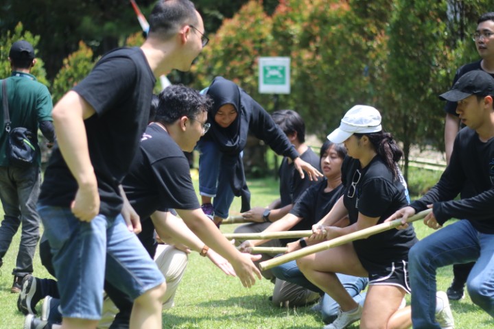 Peserta berkoordinasi menggunakan bambu dalam kegiatan outbound training